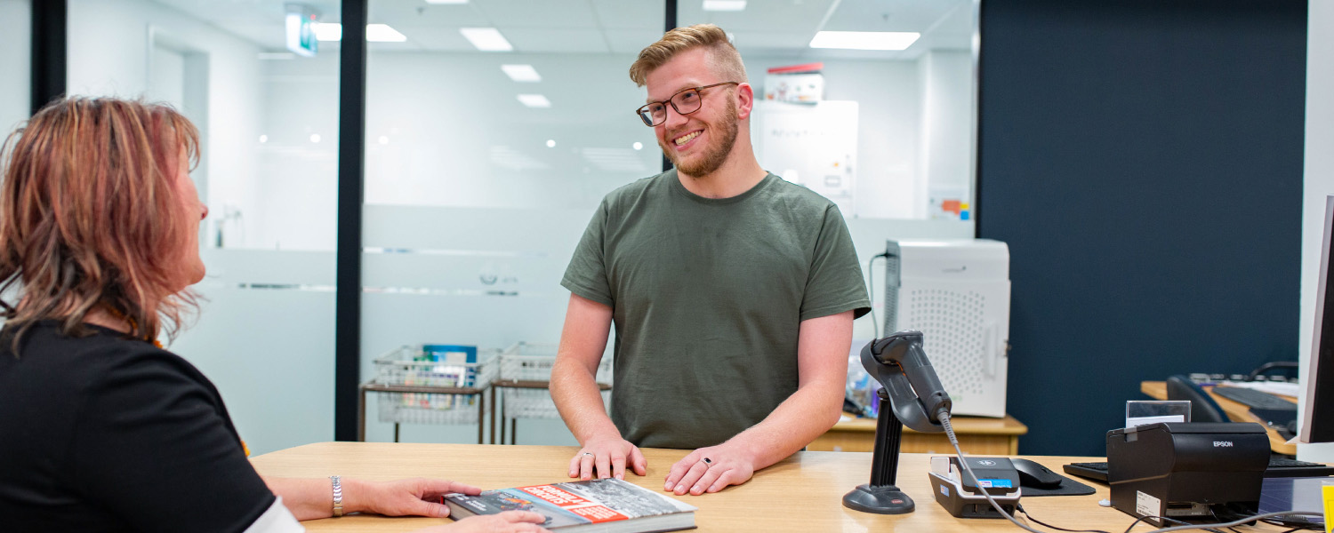 Library customer suggests a book purchase at the service desk.