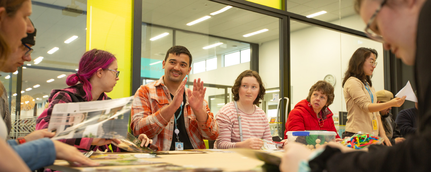 Adults taking part in a library group activity around a table.