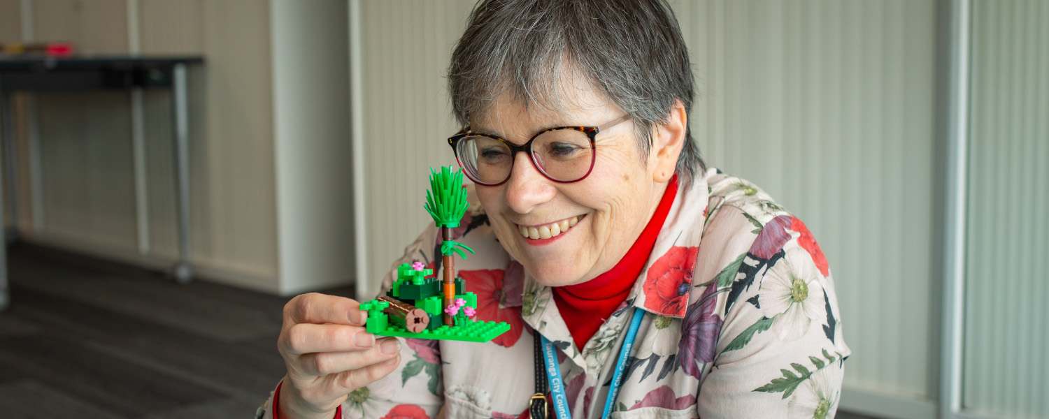 Person holding a LEGO creation during a library holiday programme.